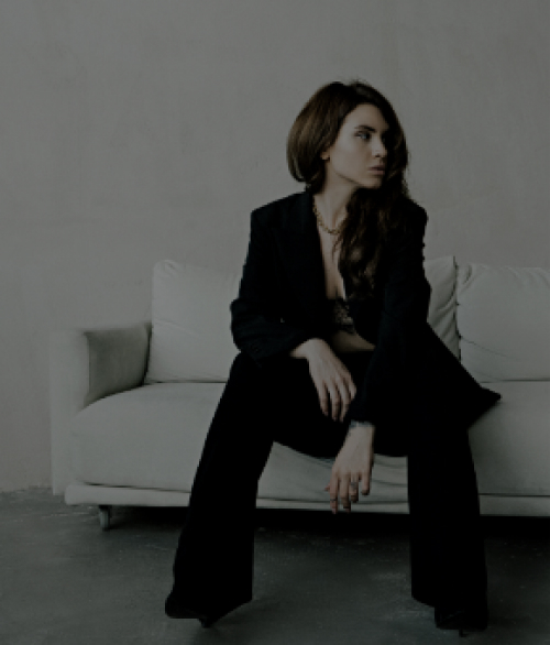 髪の長い女性が白いソファーに座っている様子